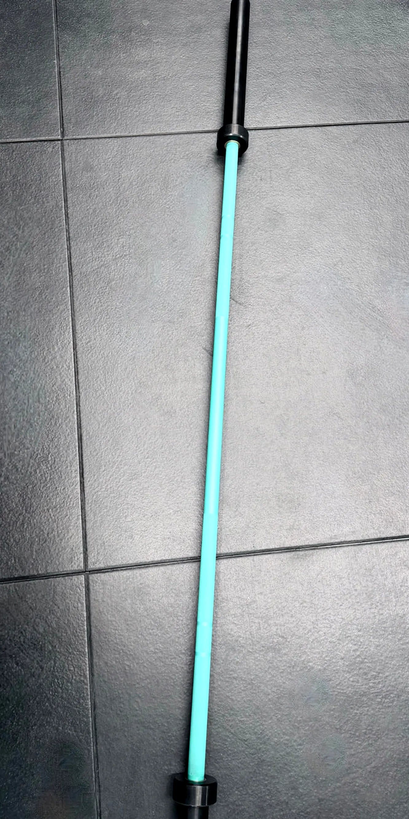 Light blue and black barbell on a gray tiled floor